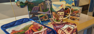 A display of available merchandise with artwork from local Nanaimo artist Francine Peters including mugs, cards, aprons, and notepads.